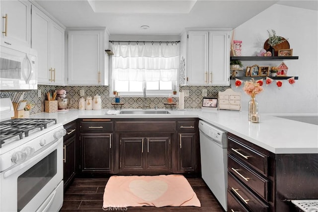 kitchen featuring tasteful backsplash, sink, a tray ceiling, dark wood-type flooring, and white appliances