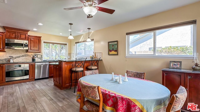 dining space with sink, light hardwood / wood-style floors, and ceiling fan