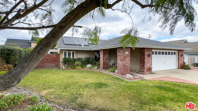 view of front of property featuring a garage, a front lawn, and solar panels