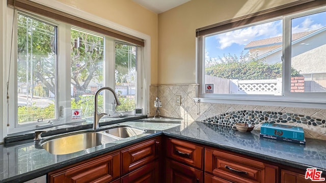 kitchen with dishwasher, sink, backsplash, and dark stone counters