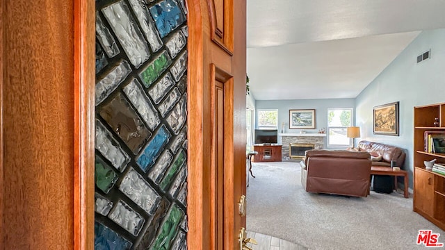 interior space featuring a stone fireplace and vaulted ceiling