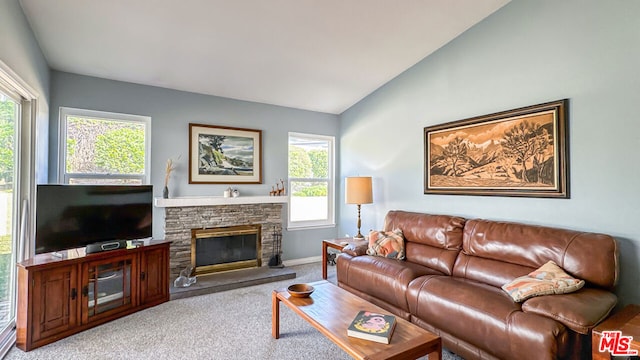 carpeted living room featuring vaulted ceiling, a stone fireplace, and a healthy amount of sunlight