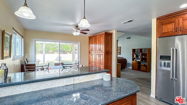 kitchen with high end fridge, hanging light fixtures, ceiling fan, dark stone counters, and light hardwood / wood-style floors