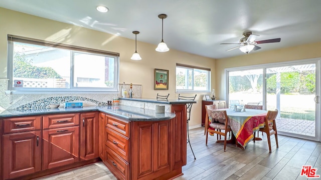 kitchen featuring decorative light fixtures, backsplash, ceiling fan, kitchen peninsula, and light wood-type flooring