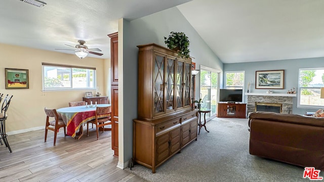 living room featuring ceiling fan, vaulted ceiling, a fireplace, and light hardwood / wood-style flooring