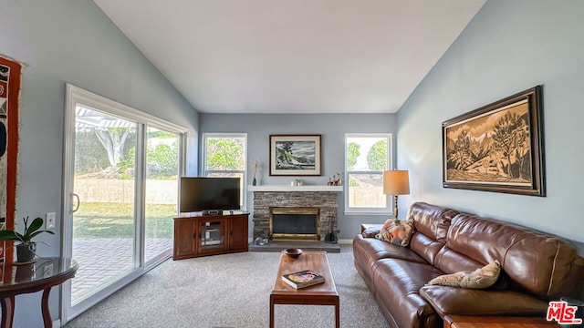 living room featuring carpet floors, a stone fireplace, vaulted ceiling, and plenty of natural light