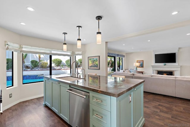 kitchen featuring dark hardwood / wood-style floors, pendant lighting, sink, stainless steel dishwasher, and a center island with sink