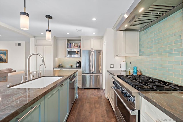 kitchen featuring wall chimney exhaust hood, sink, white cabinetry, decorative light fixtures, and stainless steel appliances