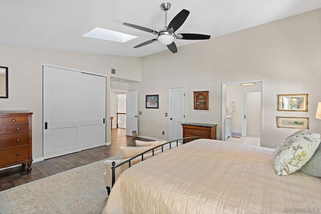 bedroom with ceiling fan, dark hardwood / wood-style floors, vaulted ceiling with skylight, and ensuite bathroom