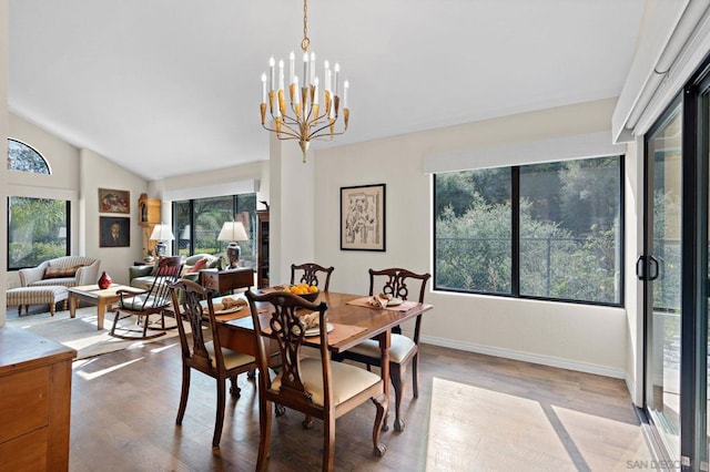 dining space featuring an inviting chandelier, vaulted ceiling, and light hardwood / wood-style flooring