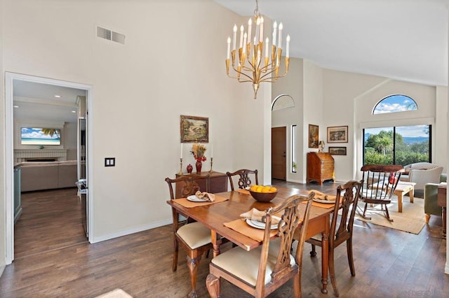 dining area featuring an inviting chandelier, dark wood-type flooring, and high vaulted ceiling