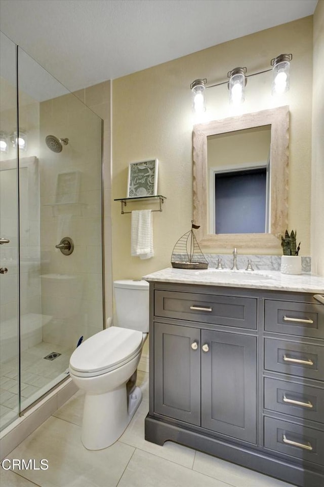 bathroom featuring vanity, tile patterned floors, a shower with door, and toilet