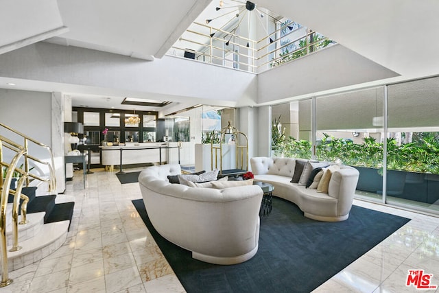 living room featuring a healthy amount of sunlight, a chandelier, and a towering ceiling