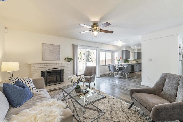 living room featuring ceiling fan, dark wood-type flooring, sink, and a fireplace