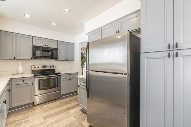 kitchen featuring stainless steel appliances, gray cabinetry, and light wood-type flooring