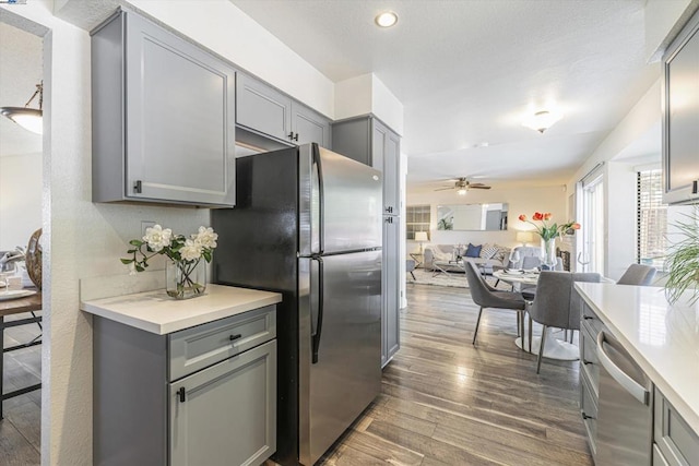 kitchen with stainless steel appliances, ceiling fan, gray cabinetry, and dark hardwood / wood-style flooring