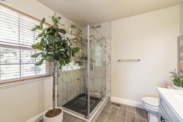 bathroom featuring vanity, a shower with door, and toilet