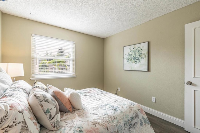 bedroom with dark hardwood / wood-style flooring and a textured ceiling