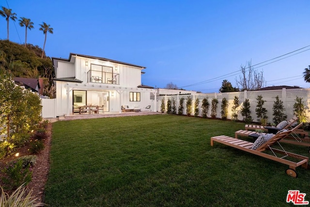 back of property with a yard, a patio, and a balcony