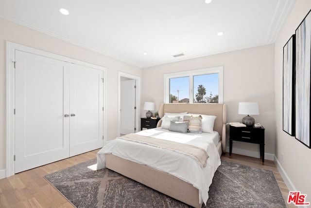 bedroom with ornamental molding, wood-type flooring, and a closet