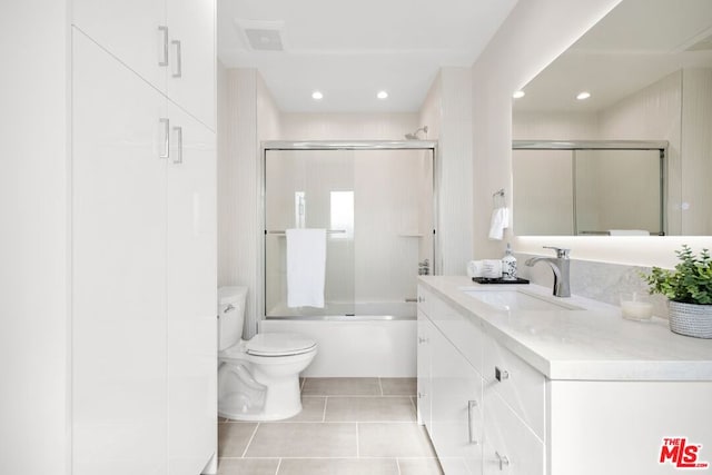 full bathroom with tile patterned flooring, enclosed tub / shower combo, vanity, and toilet