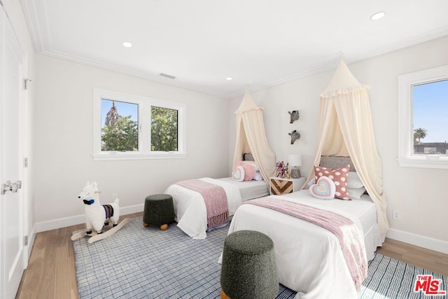 bedroom with hardwood / wood-style flooring, crown molding, and multiple windows