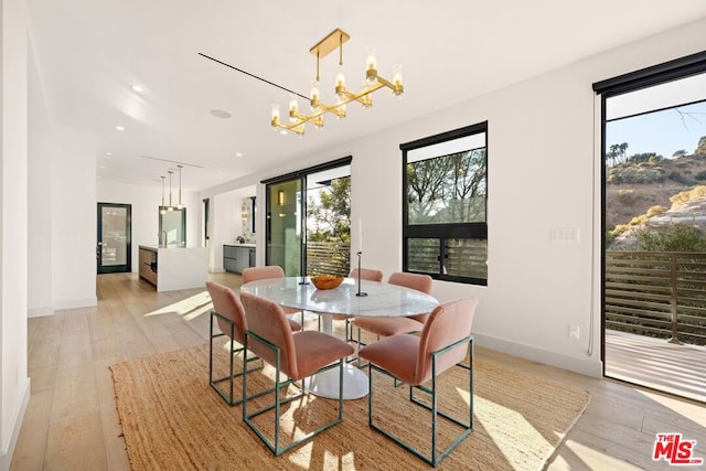 dining space with light hardwood / wood-style floors and a notable chandelier