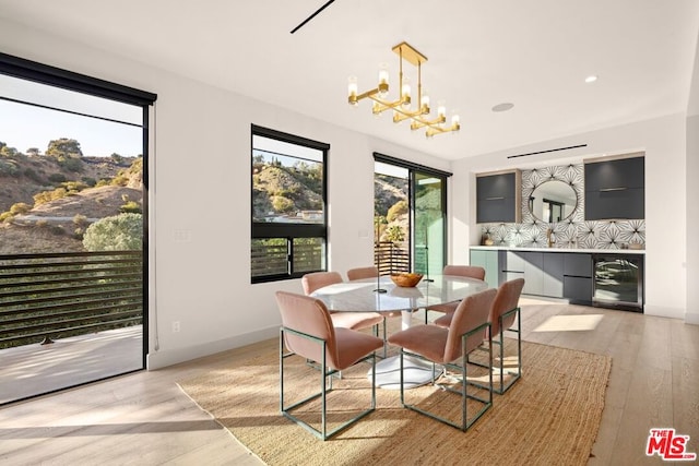 dining room with beverage cooler, light hardwood / wood-style flooring, and a notable chandelier