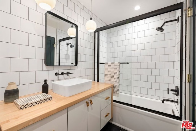 bathroom featuring tile walls, vanity, decorative backsplash, and bath / shower combo with glass door