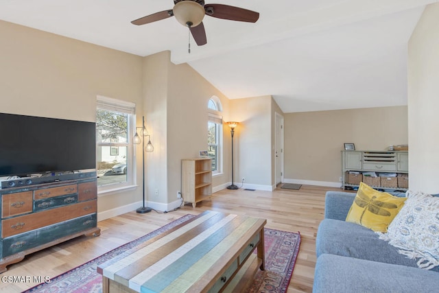 living room with ceiling fan, vaulted ceiling, and light wood-type flooring