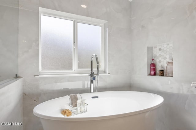 bathroom with tile walls and a bathtub