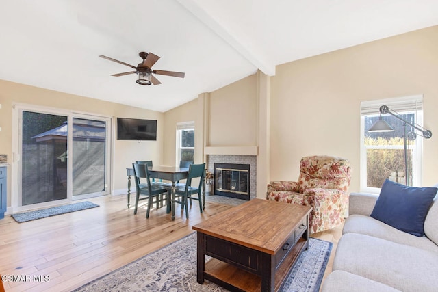 living room featuring ceiling fan, plenty of natural light, light hardwood / wood-style floors, and lofted ceiling with beams