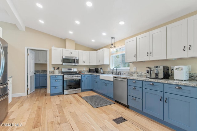 kitchen with appliances with stainless steel finishes, sink, white cabinets, light hardwood / wood-style floors, and blue cabinetry