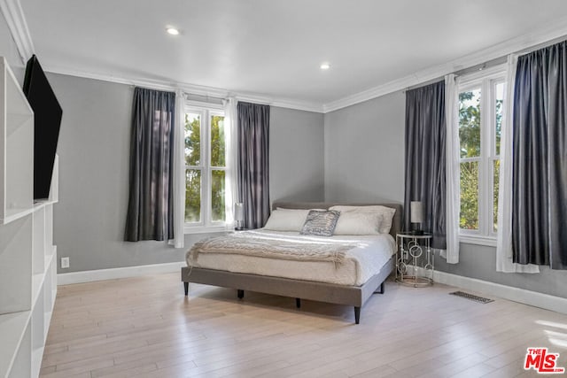 bedroom featuring multiple windows, crown molding, and light wood-type flooring