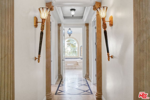 hall with a raised ceiling, ornamental molding, and ornate columns