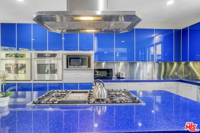 kitchen with white cabinetry, blue cabinets, range hood, and appliances with stainless steel finishes