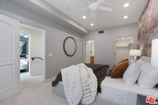 carpeted bedroom featuring a spacious closet, ensuite bath, and ceiling fan