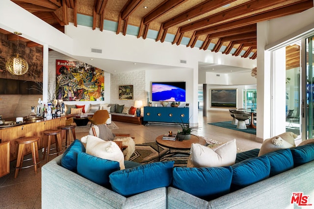 living room featuring bar, a towering ceiling, and beamed ceiling