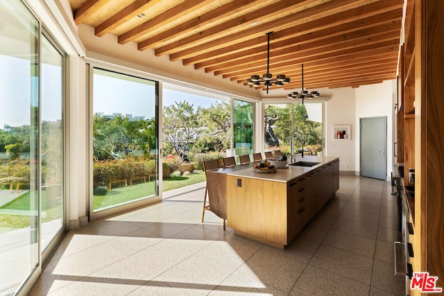 sunroom featuring beam ceiling and sink