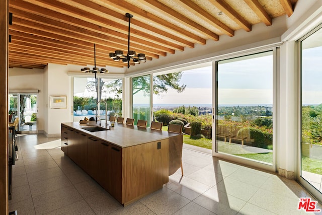 sunroom / solarium featuring sink, a notable chandelier, and beam ceiling