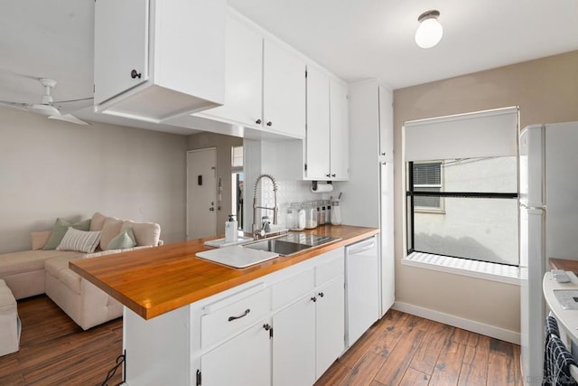 kitchen featuring dark wood-type flooring, sink, kitchen peninsula, white appliances, and white cabinets