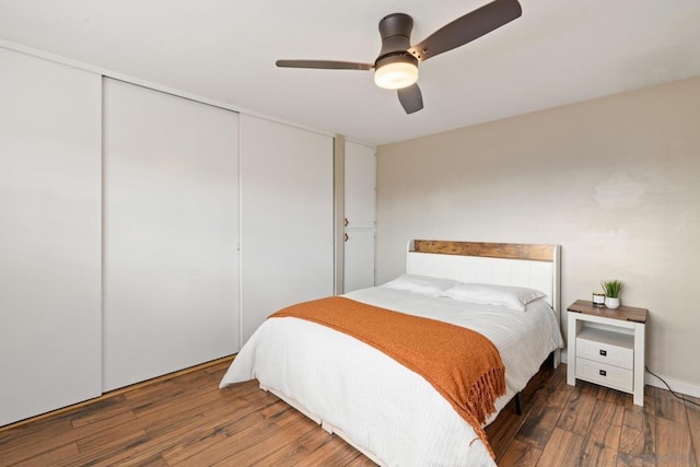 bedroom featuring dark wood-type flooring, ceiling fan, and a closet