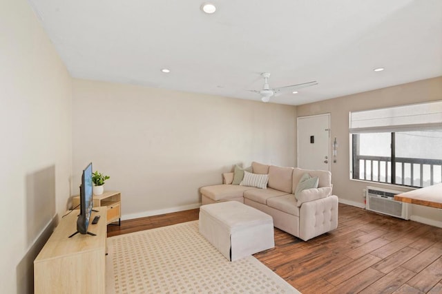 living room featuring wood-type flooring, an AC wall unit, and ceiling fan