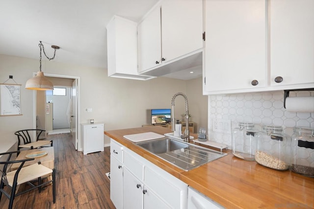 kitchen with pendant lighting, sink, dark wood-type flooring, white cabinetry, and backsplash