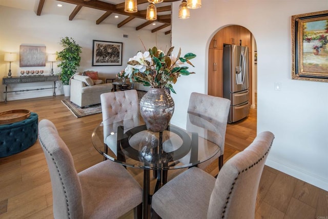 dining room featuring a notable chandelier, light hardwood / wood-style flooring, and beamed ceiling