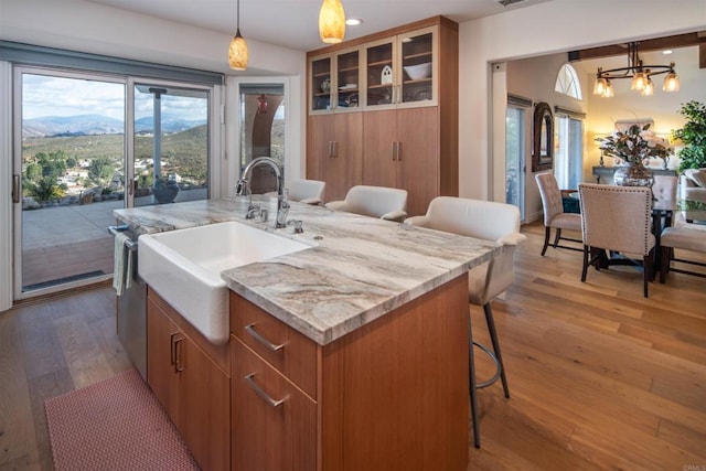 kitchen featuring a breakfast bar, hardwood / wood-style floors, a center island with sink, a mountain view, and decorative light fixtures