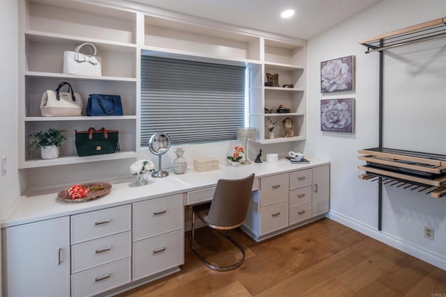 home office with hardwood / wood-style floors, built in shelves, and built in desk