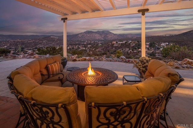 patio terrace at dusk featuring a mountain view and an outdoor living space with a fire pit