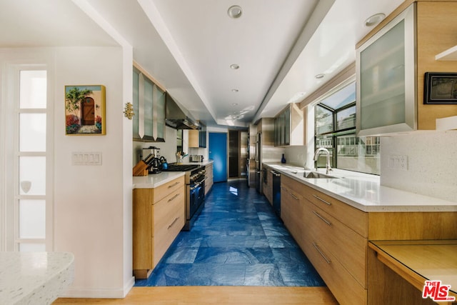 kitchen featuring decorative backsplash, sink, high end stove, and wall chimney range hood