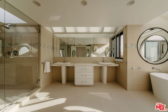 bathroom with tile patterned flooring, separate shower and tub, sink, and tile walls